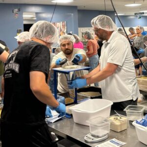 Pax help make boxes of food at Feed May starving Children in May 2024.